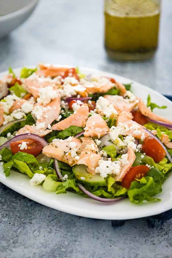 Fresh salmon salad with lettuce, tomatoes, cucumbers, feta cheese, and baked salmon.