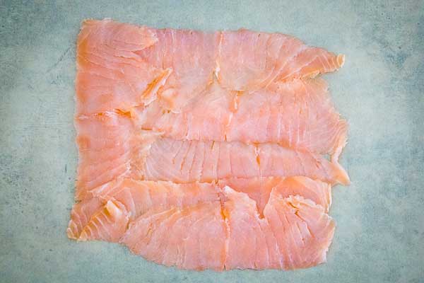 Thin slices of smoked salmon laid flat on a light surface.