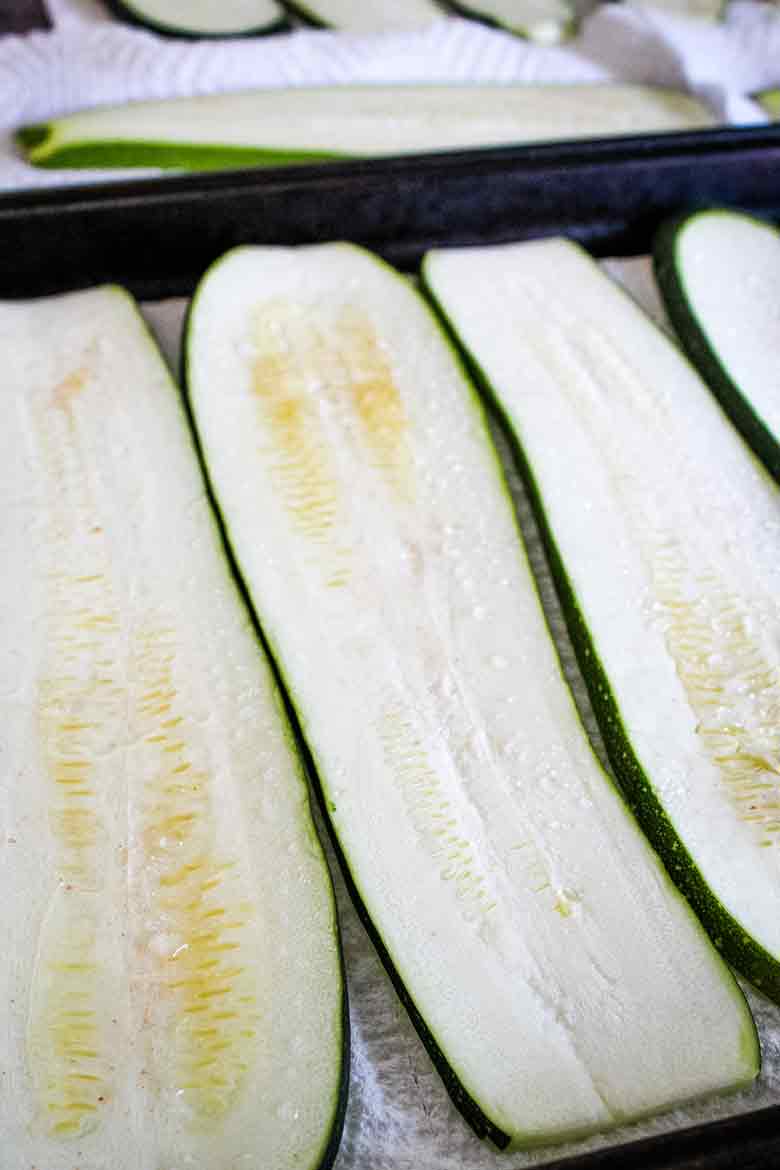 Long slices of fresh zucchini laid out on paper towels to remove excess moisture.