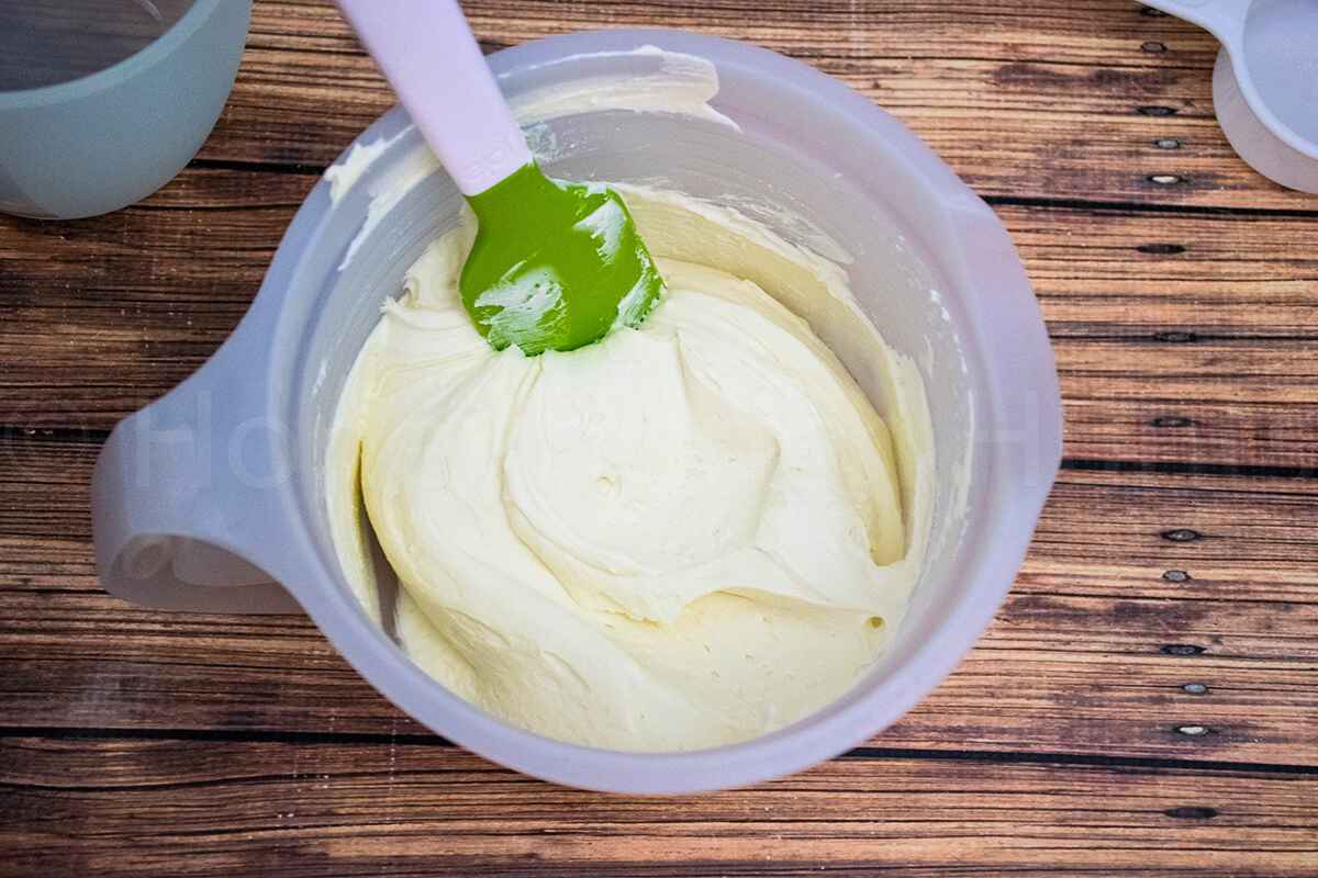 Bowl of smooth ricotta cream filling with a spatula for cannoli poke cake.