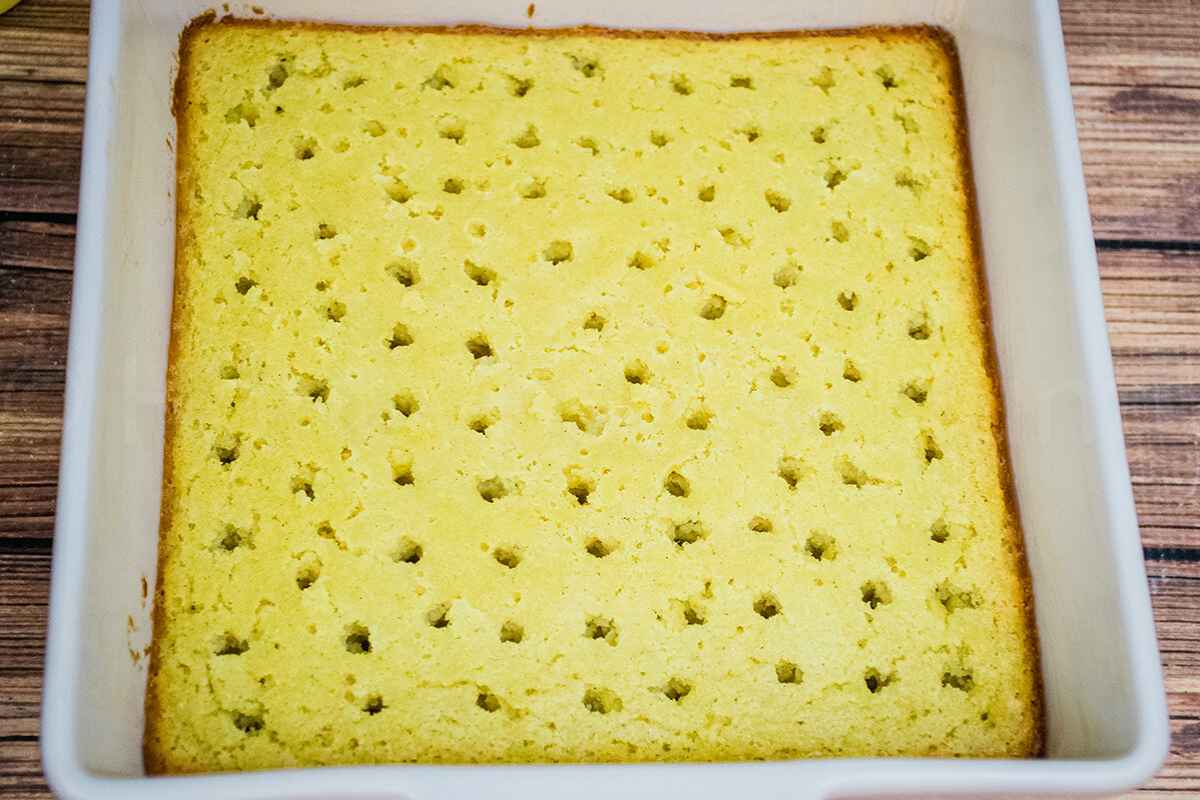 Baked yellow cake in a pan with evenly spaced holes ready for filling.