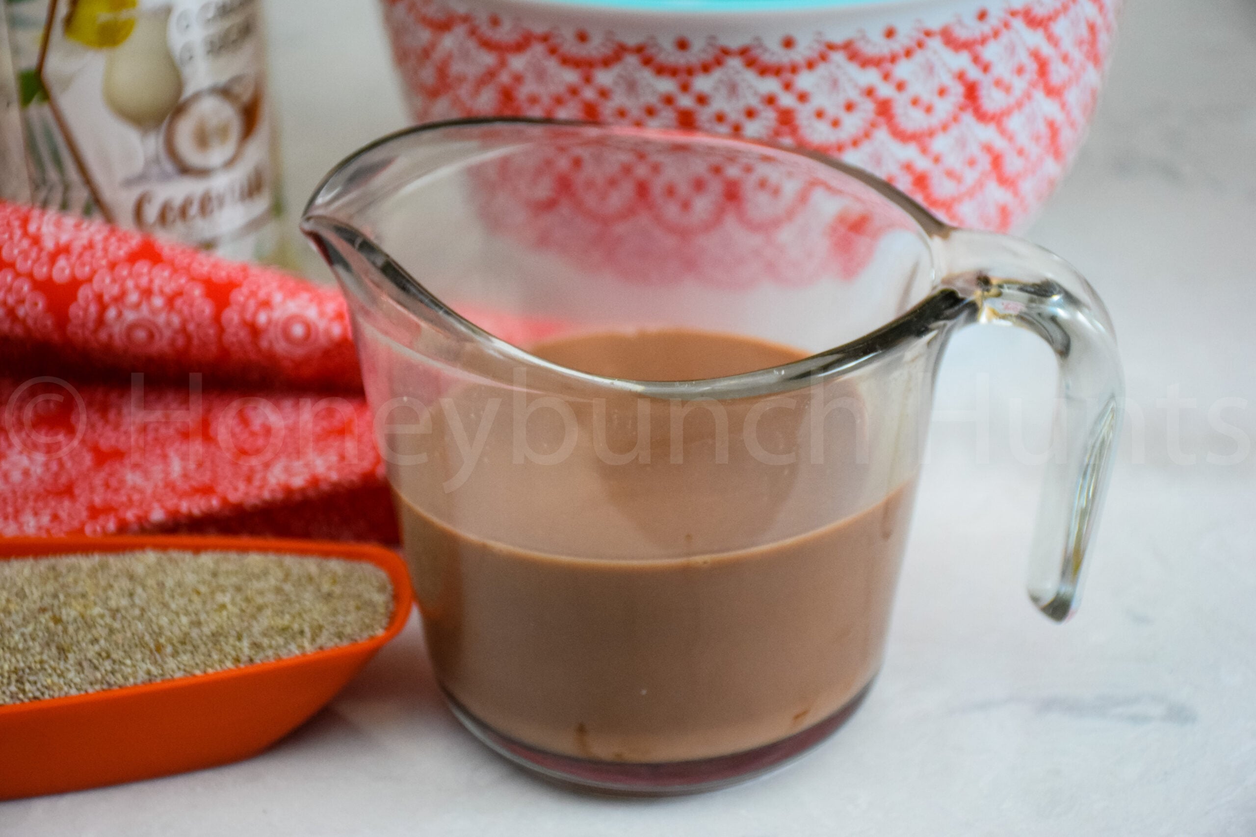 Glass measuring cup filled with chocolate milk mixture next to chia seeds.