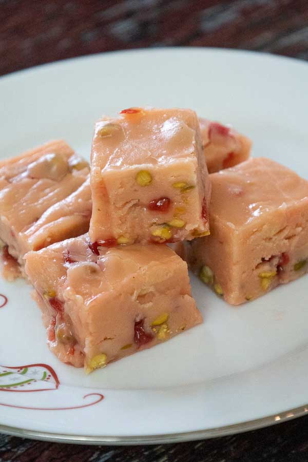 Plate of creamy eggnog fudge squares with cherries and pistachios.