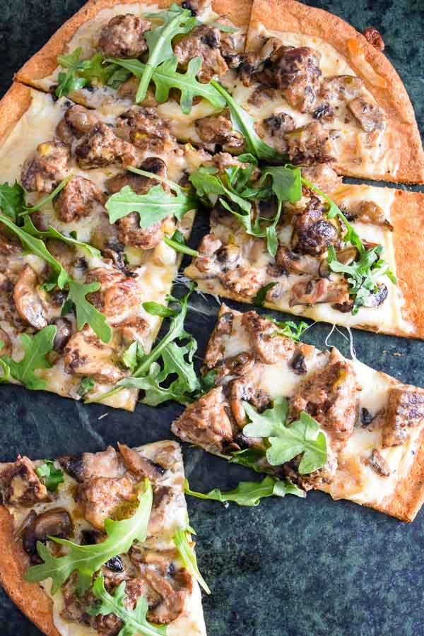 A golden baked pizza with melted cheese, mushrooms, and meatballs.