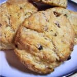 Golden brown pecan sour cream biscuits stacked on a plate, showing a flaky texture with bits of pecan inside.