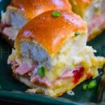Sweet and Spicy Ham and Cheese Slider with melted cheese and pepper jelly on fluffy dinner rolls garnish with finely diced jalapeno.