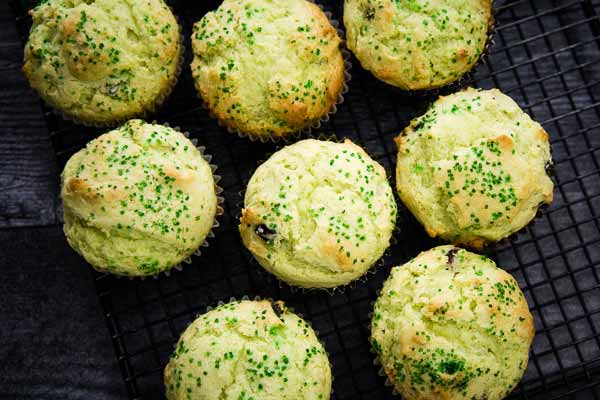 Overhead view of freshly baked muffins with greens ugar sprinkles cooling on a wire rack.