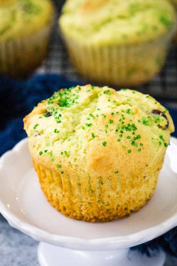 Single Pistachio cherry muffin topped with green sugar crystals on a white plate.