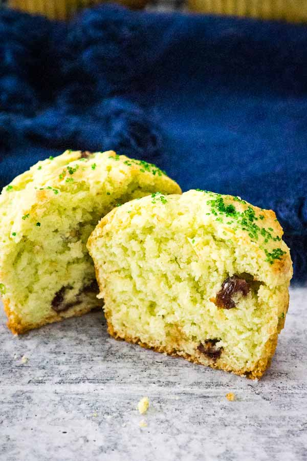 Pistachio cherry muffin cut in half showing fluffy texture and pieces of cherries inside.
