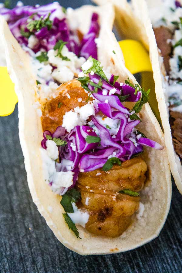 Easy shrimp taco with grilled shrimp, red cabbage slaw, cotija cheese, and cilantro in a soft tortilla.