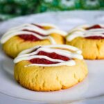 Keto Thumbprint Cookies with Strawberry Rhubarb drizzled with a white glaze on a white plate.
