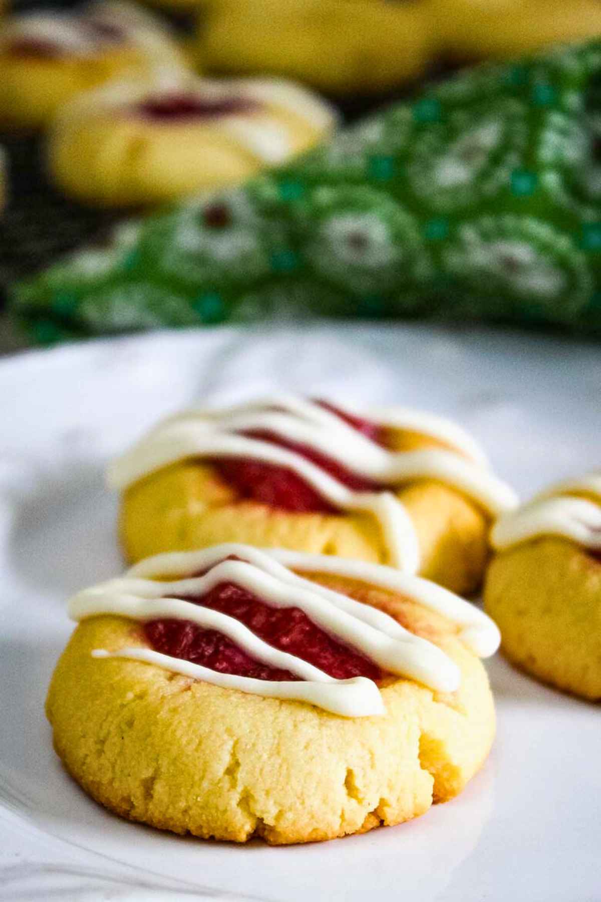 Keto Thumbprint Cookies with Strawberry Rhubarb drizzled with a white glaze on a white plate.