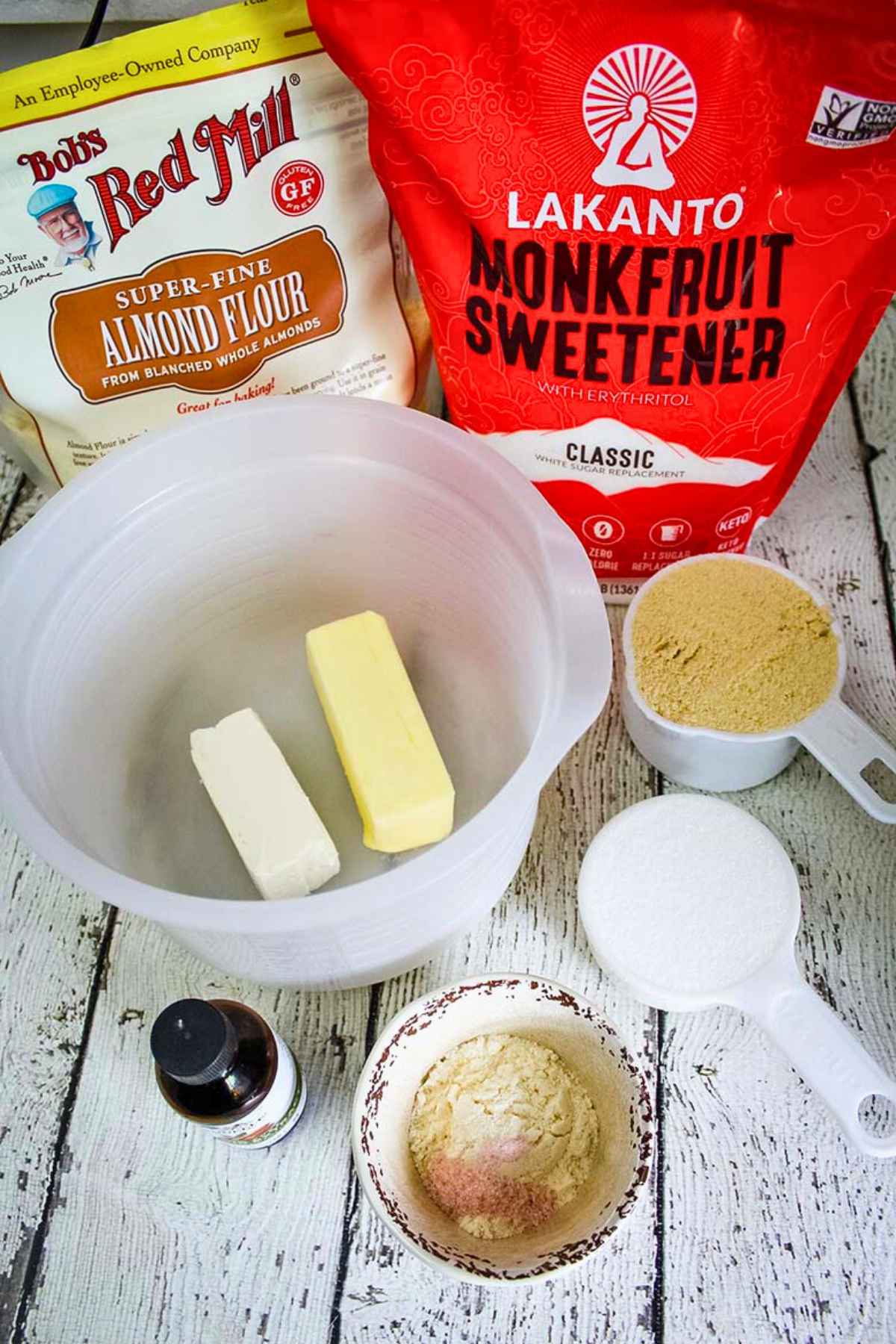 Baking ingredients laid out including almond flour, monkfruit sweetener, butter, cream cheese, vanilla extract, in measured portions.