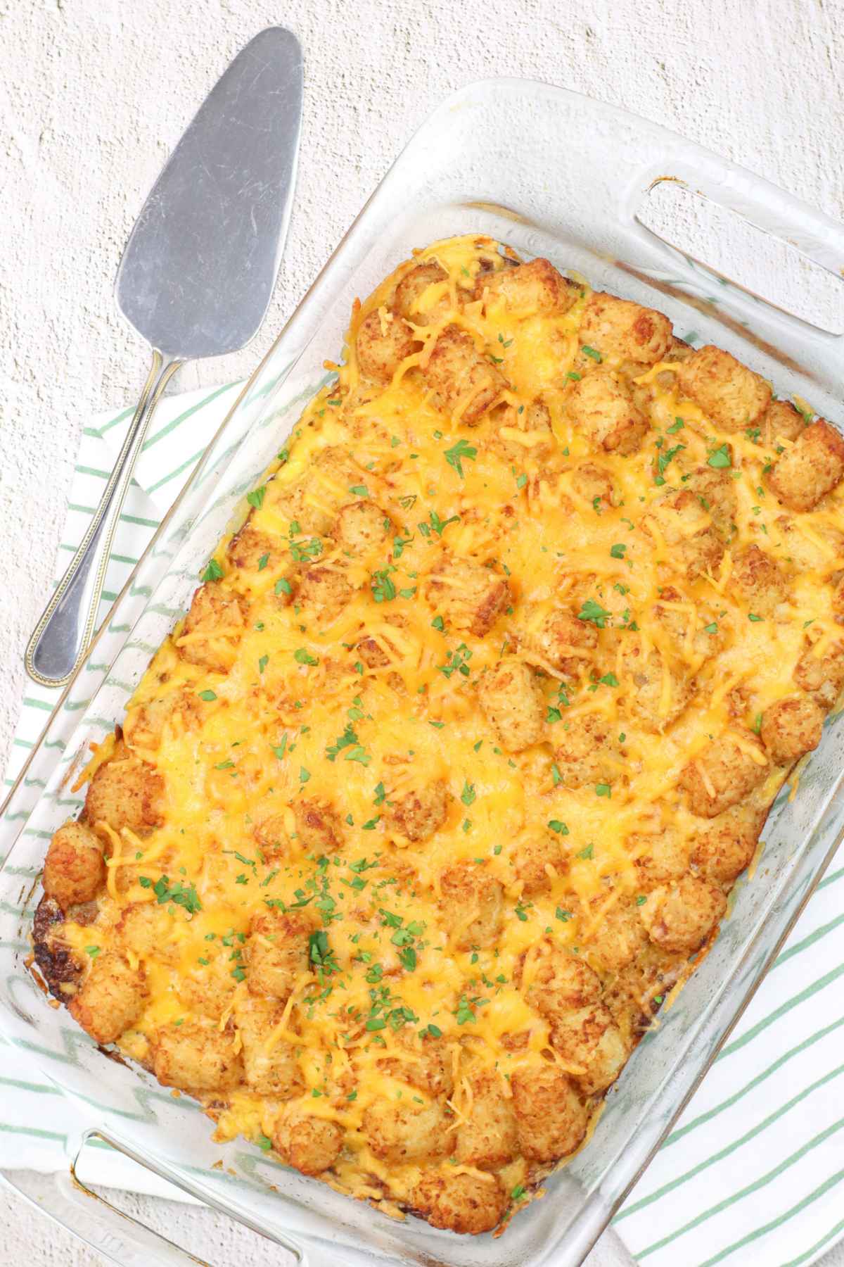 Glass baking dish filled with golden baked tater tot breakfast casserole topped with melted cheese.