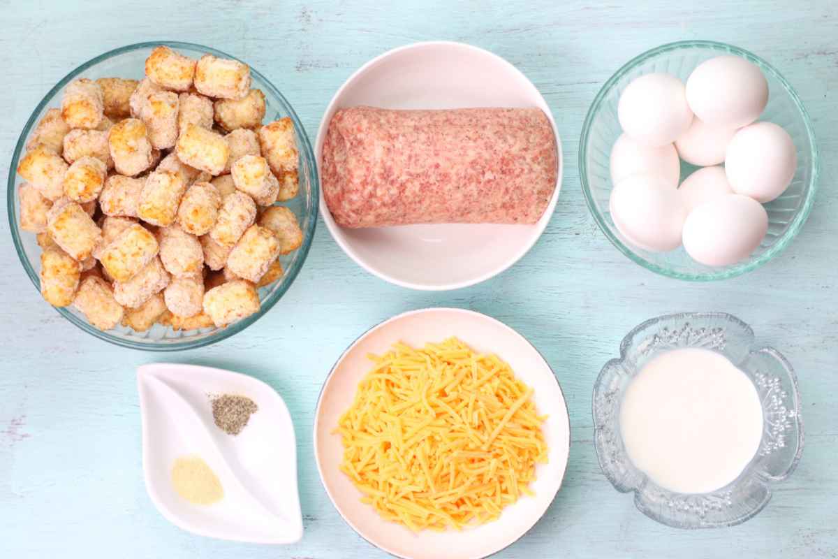 Casserole ingredients including a bowl of sausage, eggs, cheese, milk, and frozen tater tots.