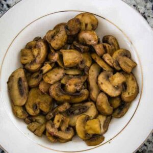 Umami mushrooms served in a white bowl with a gold rim.