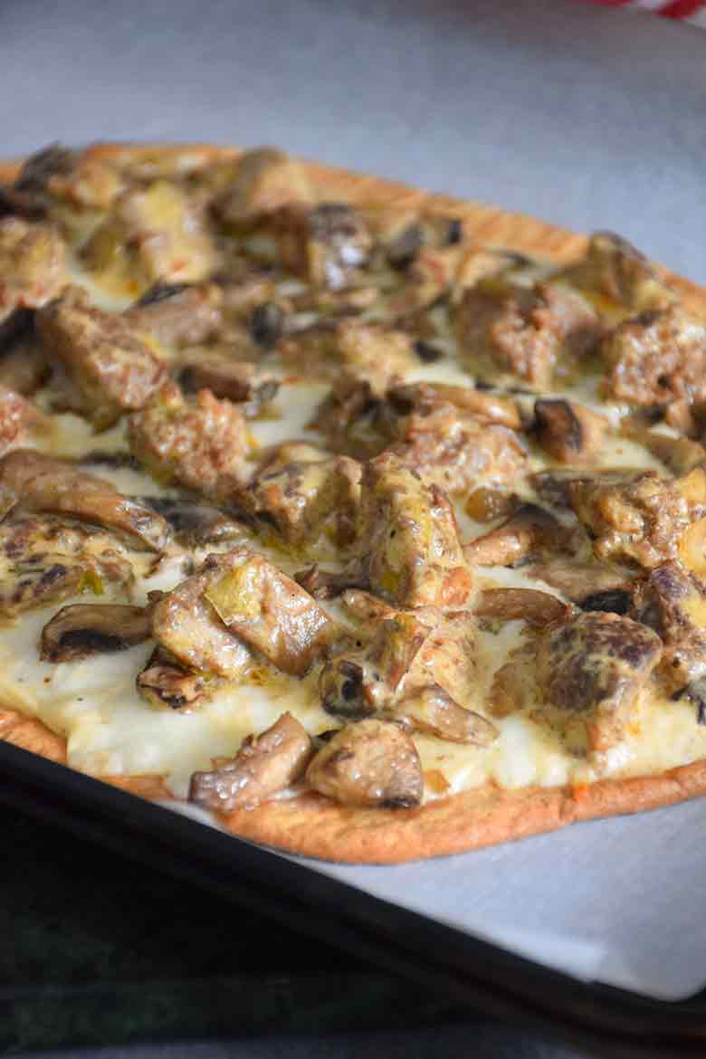 A baked Keto Meatball Alfredo Pizza before sprinkling with arugula.