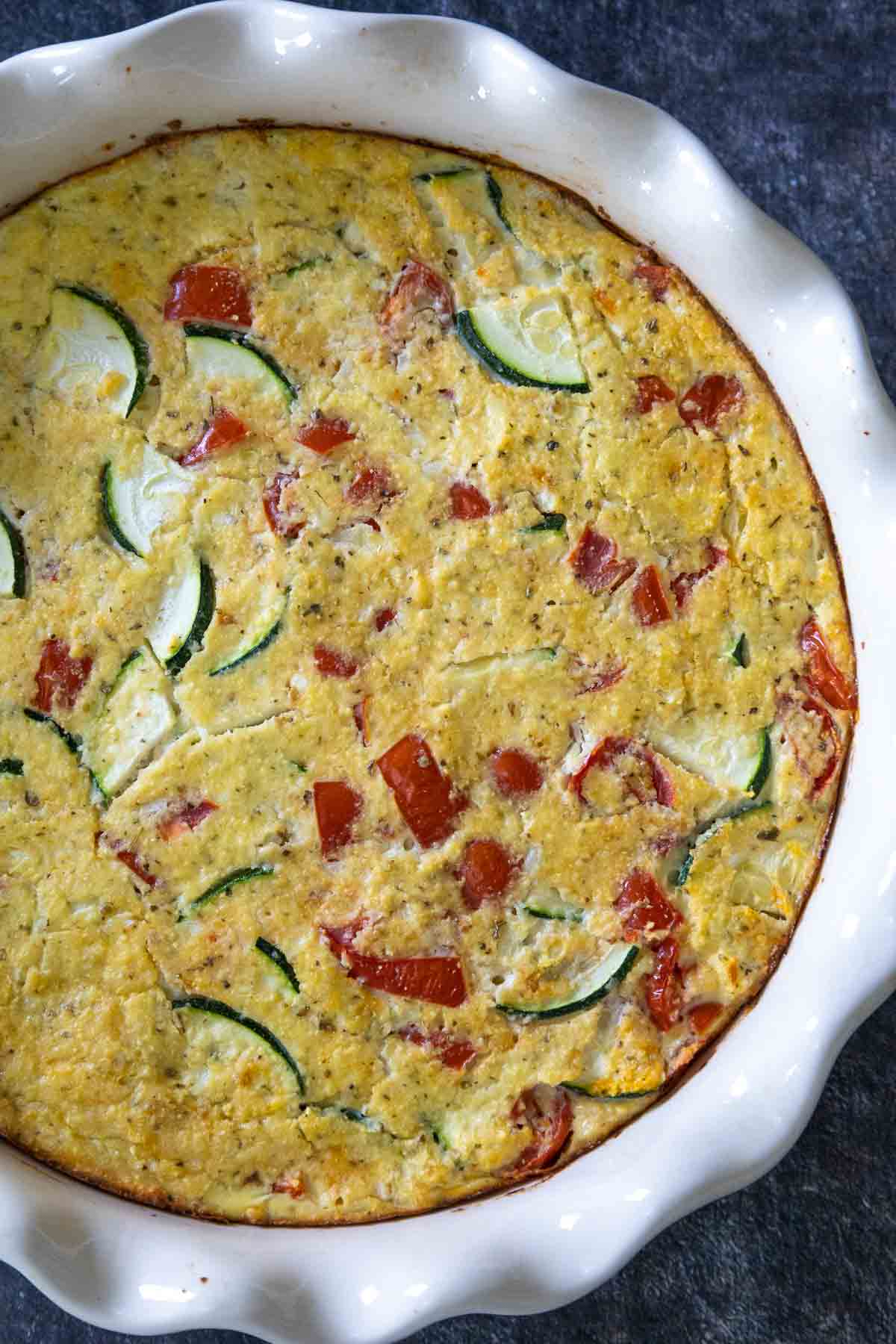 Golden brown baked keto zucchini pie in a white fluted-edge baking dish.