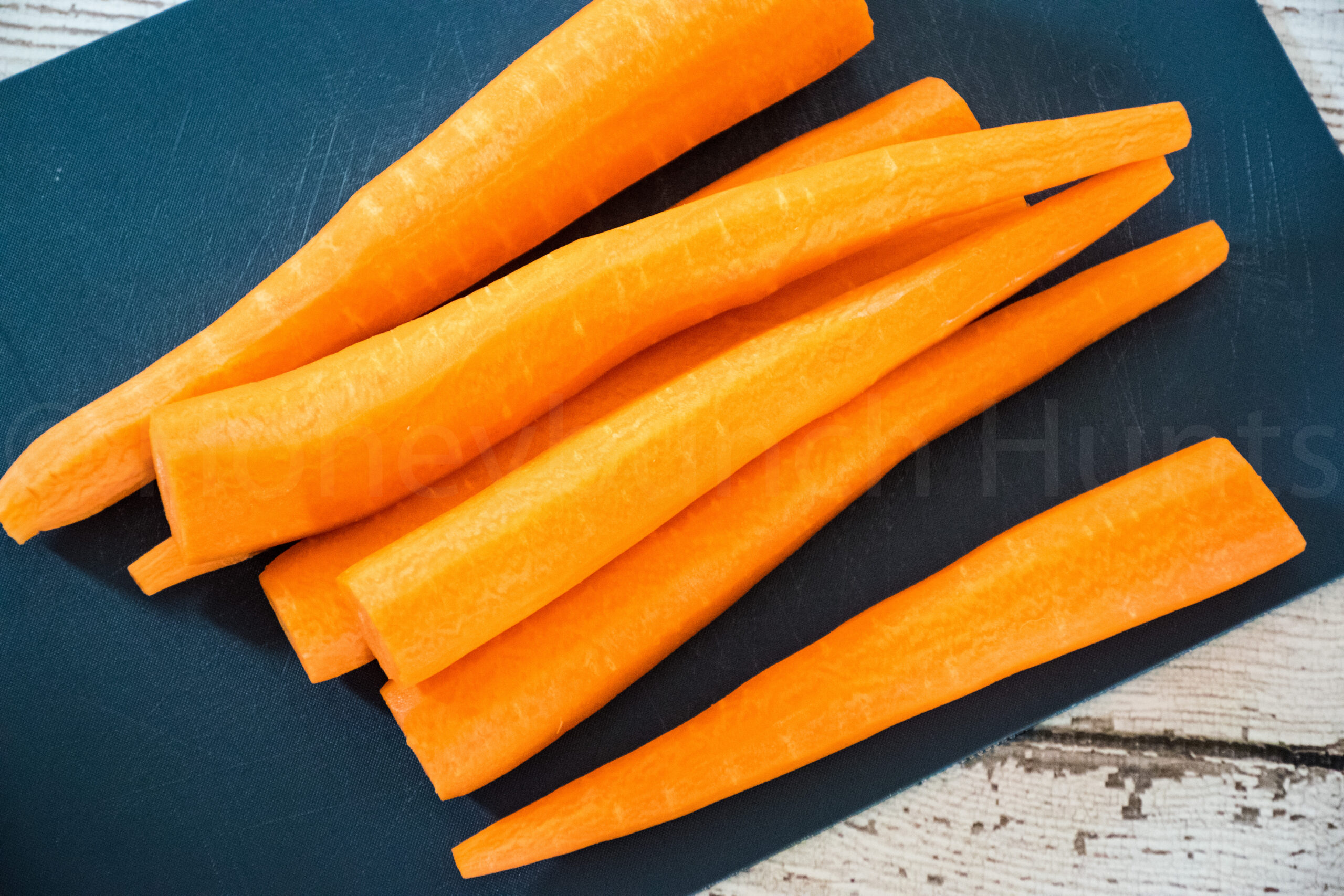 Fresh peeled carrots on a cutting board ready to be sliced.