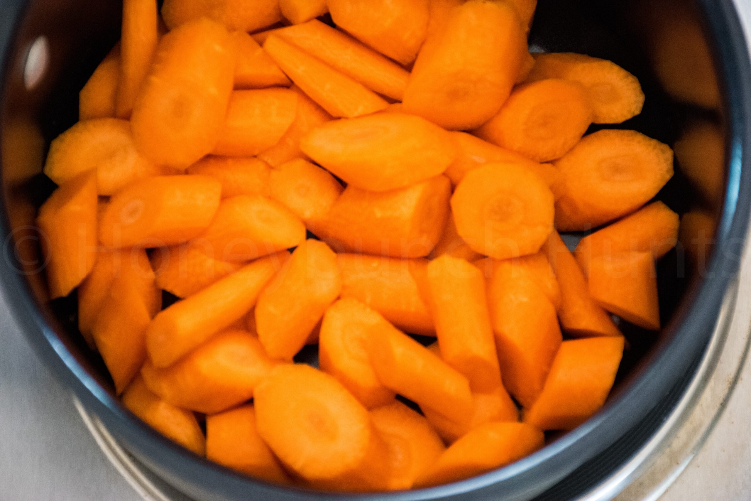 Sliced raw carrots in a pot before cooking.
