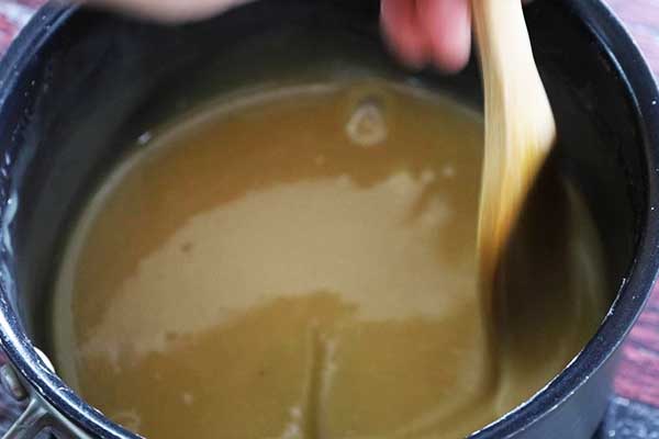 Fudge mixture being stirred in a saucepan with a wooden spoon.