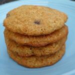 A stack of 4 banana chocolate chip cookies on a blue plate.