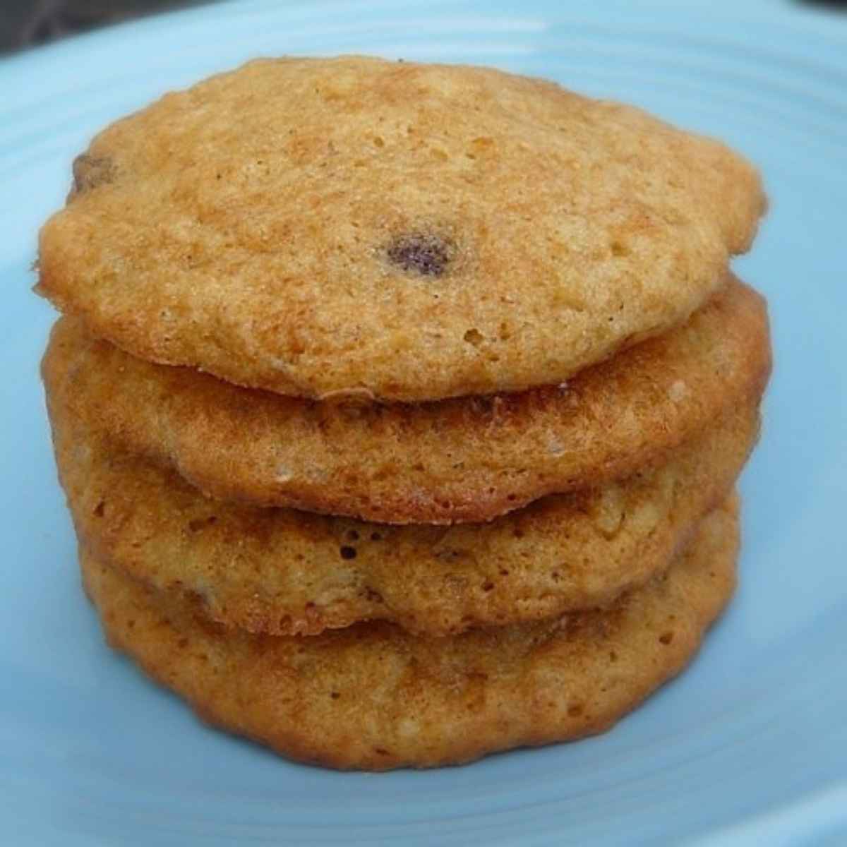 A stack of 4 banana chocolate chip cookies on a blue plate.