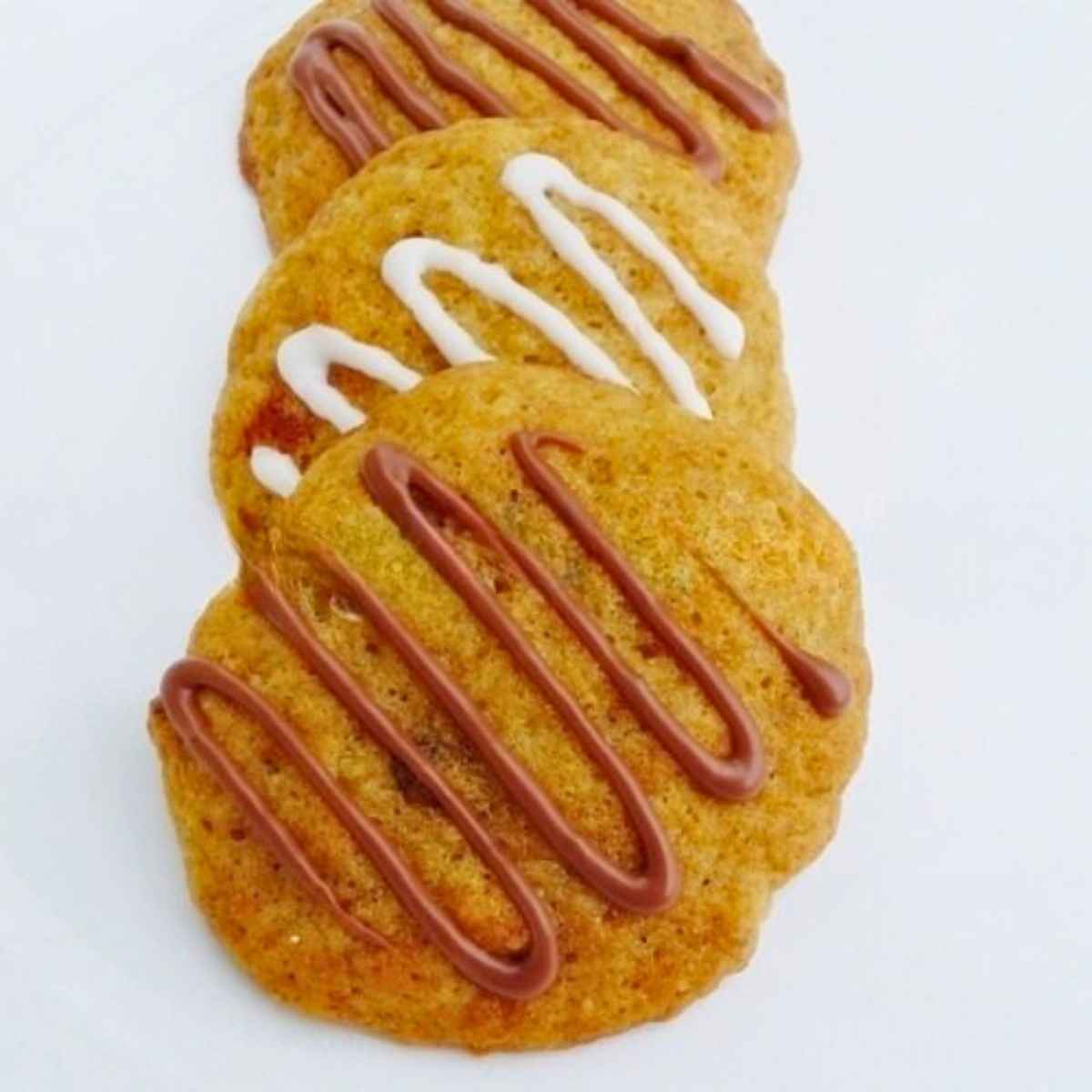 3 cookies slightly stacked drizzled with chocolate and vanilla frosting.