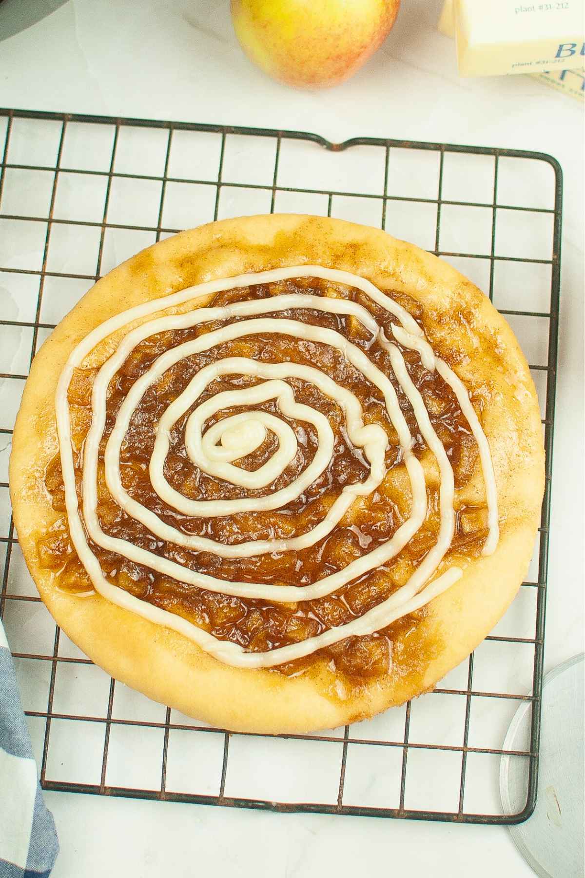 Caramel Apple Dessert Pizza on a cooling rack with the vanilla icing drizzle.