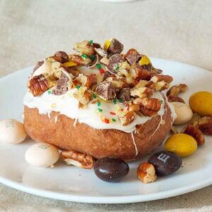 Caramel Apple Doughnuts with Caramel Frosting topped with candy pieces, chopped pecans, and fall sprinkles.