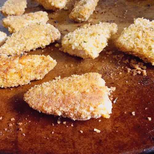 An upclose look at breaded chicken pieces baked on a baking stone with a golden, crispy coating.