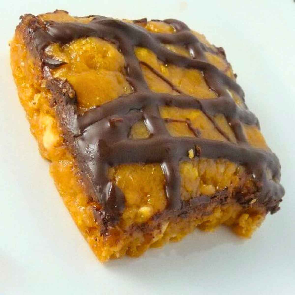 A close up of a single peanut butter cereal bar topped with a chocolate drizzle, showing its chewy texture and nutty bits.
