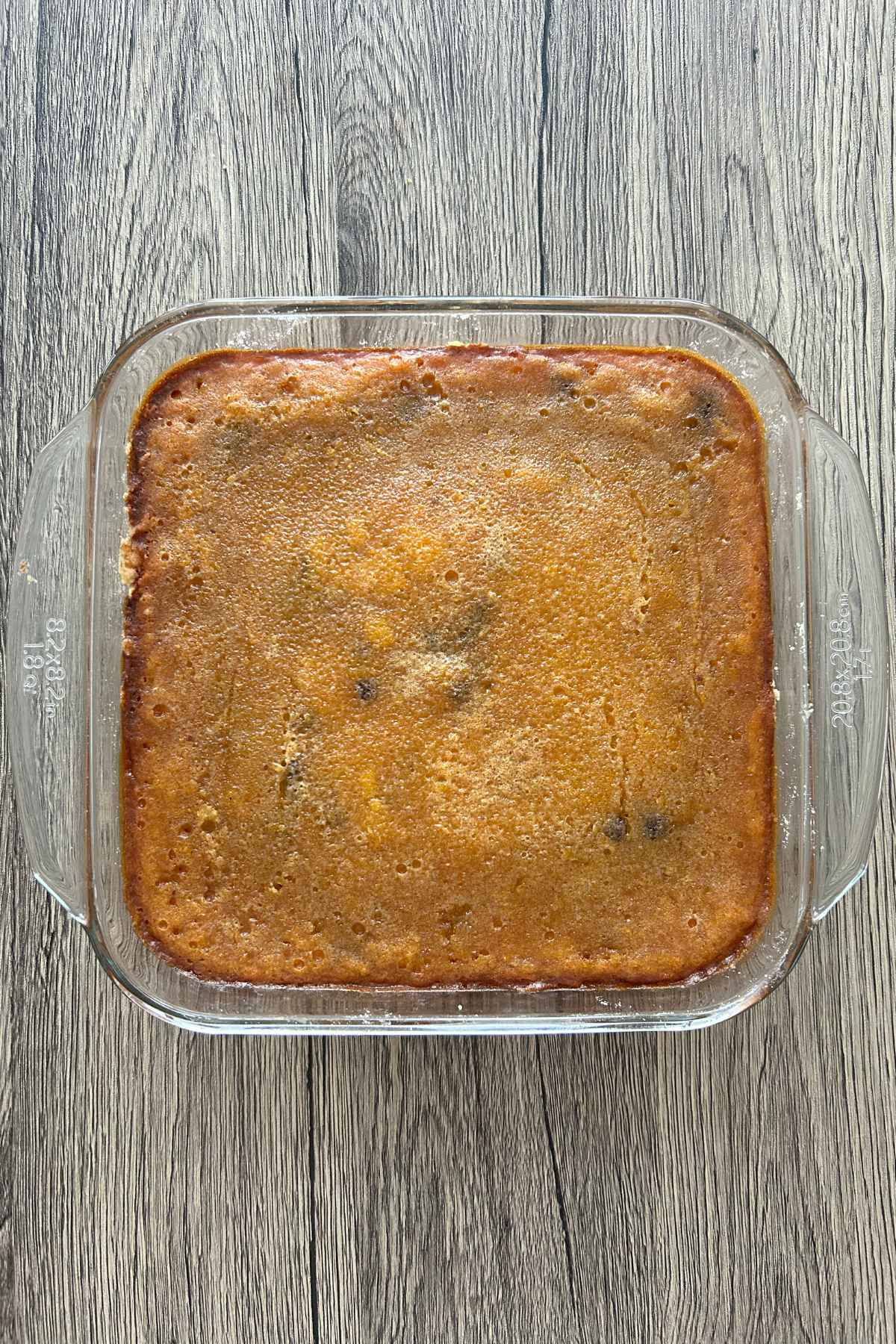Overhead view of a freshly baked pan of pumpkin chocolate chip bars in a glass baking dish with a golden brown top.