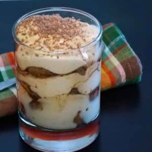 Pumpkin tiramisu layered in a glass dusted with grated chocolate.