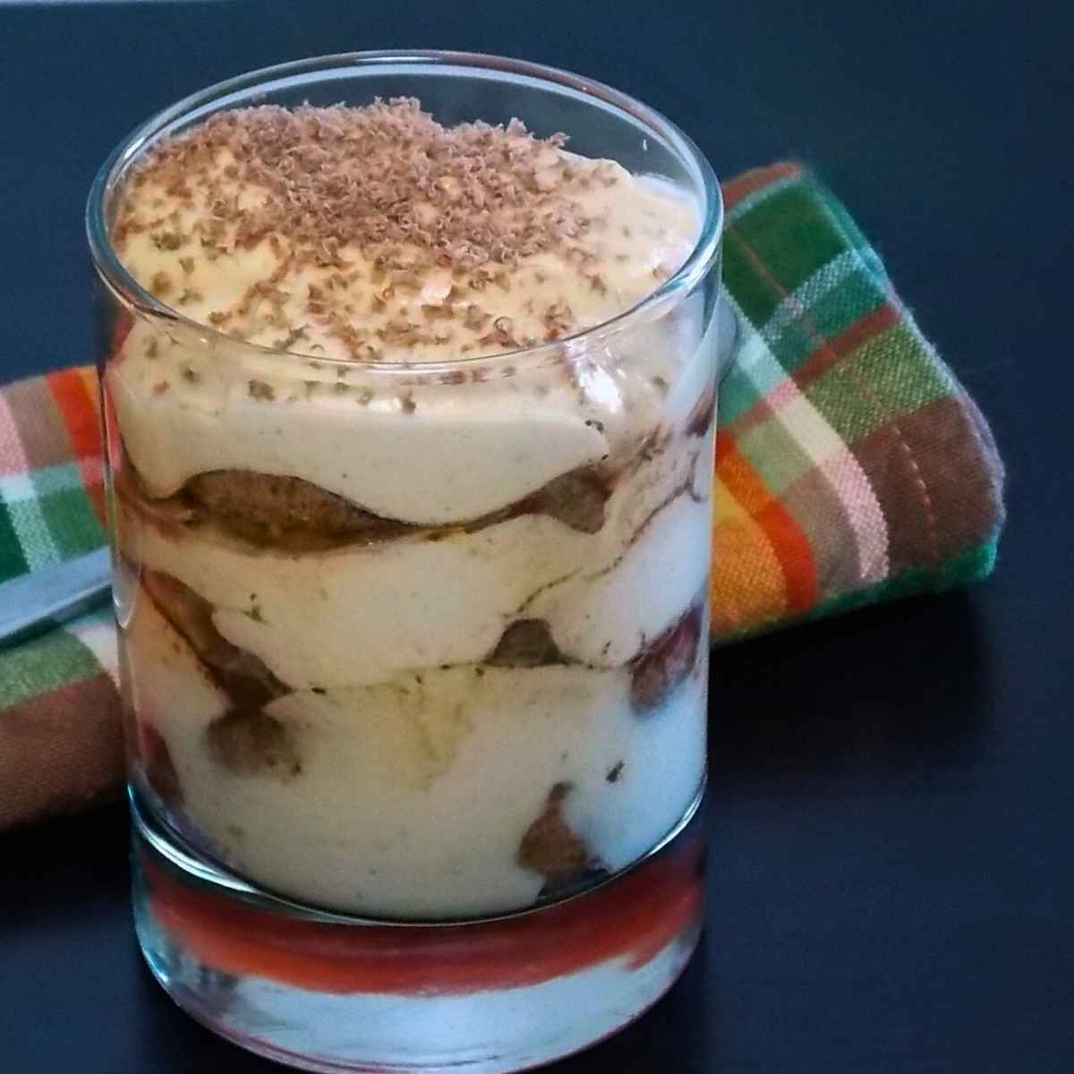 Pumpkin tiramisu layered in a glass dusted with grated chocolate.