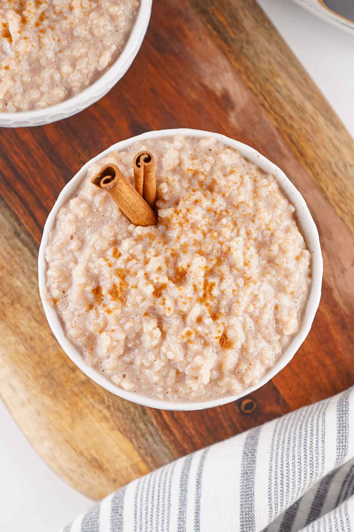 Overhead view of a bowl of rice pudding topped with cinnamon and two cinnamon sticks.