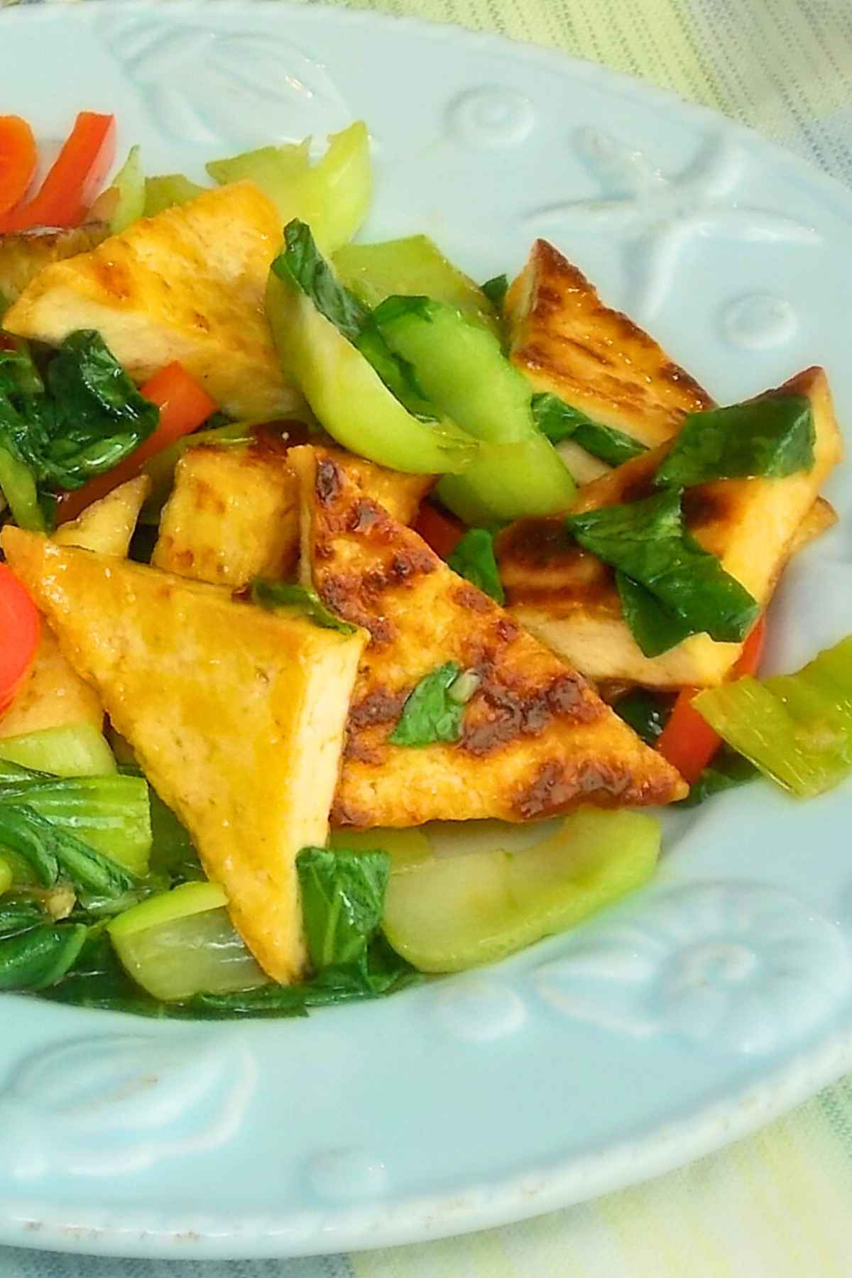 Bok Choy Tofu Stir Fry with crispy brown triangular pies of tofu coated in a sauce with stir fried bok choy and red bell pepper.