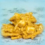 A closeup of a butterscotch haystack cookie made with melted butterscotch chips, chow mein noodles, and mini marshmallows, piled into an irregular mound on a snowflake patterned plate.