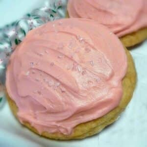 Two pink frosted craisins filled cookies on a white tray.