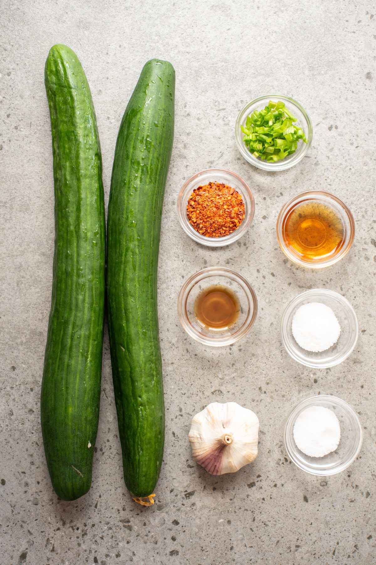 Flat lay of ingredients to include Cucumbers, a head of garlic, spices, apple cider vinegar, and fish sauce.