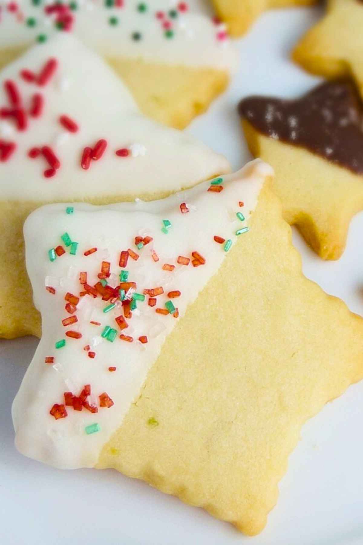 A pile of lime shortbread cookies dipped in chocolate and decorated with sprinkles.