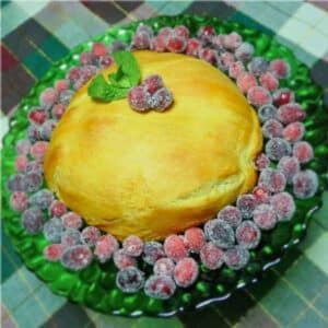 Maple Pecan Baked Brie on a green serving platter surrounded by sugared cranberries and garnished with mint.