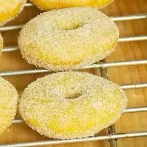 Baked Pumpkin Spice Donuts coated in cinnamon sugar on a cooling rack.