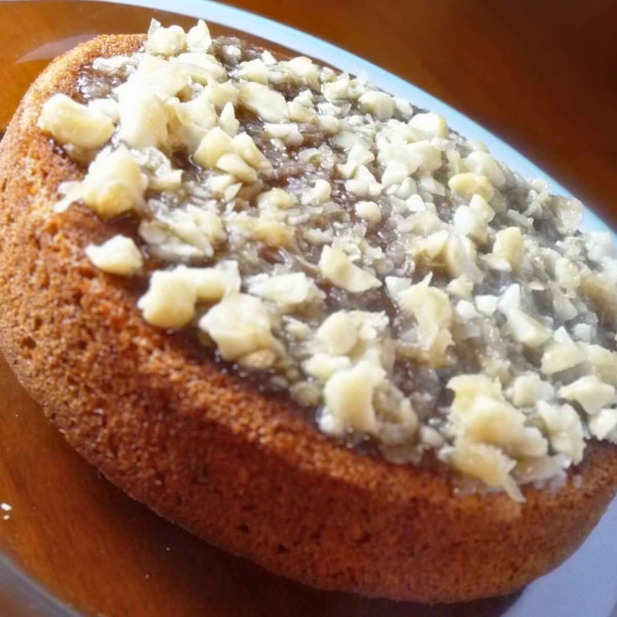 A whole banana macadamia cake on a glass cake plate with a light blue trim.