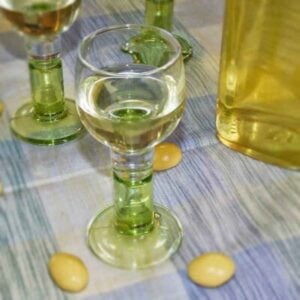Limoncello glasses filled with homemade limoncello recipe and yellow candy coated almonds scattered around the glasses.