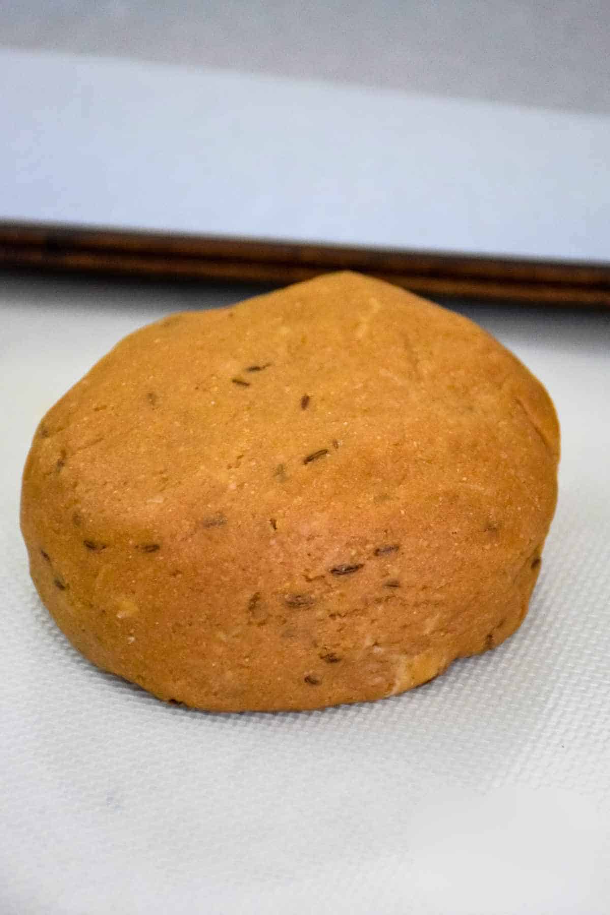 Close up of a single ball of dough, lightly textured with seeds, ready for shaping.