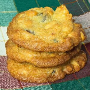 A stack of three kitchen sink cookies on a red, green and gold patchwork napkin.