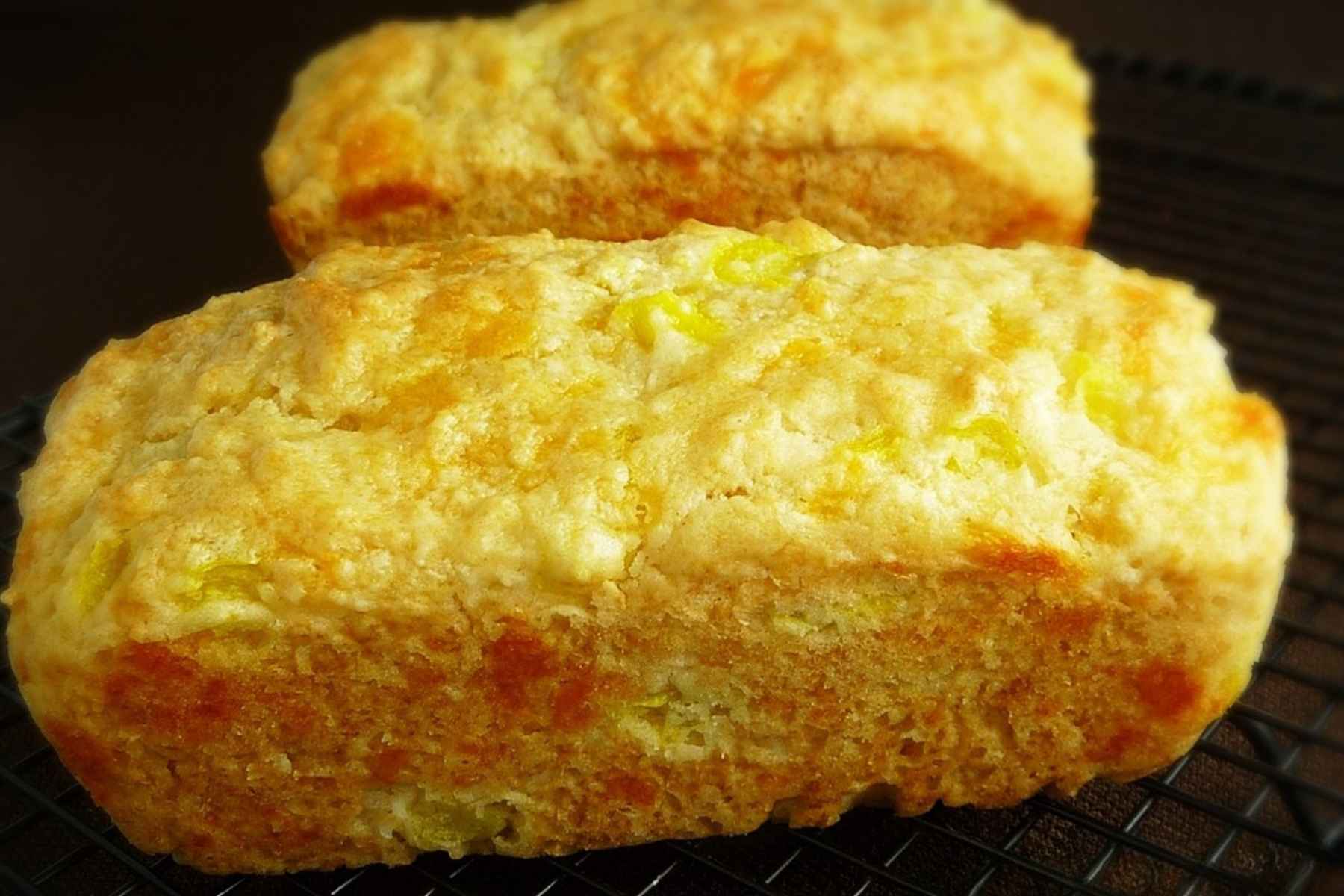 Two mini loaves of beer cheese bread cooling on a cooling rack.