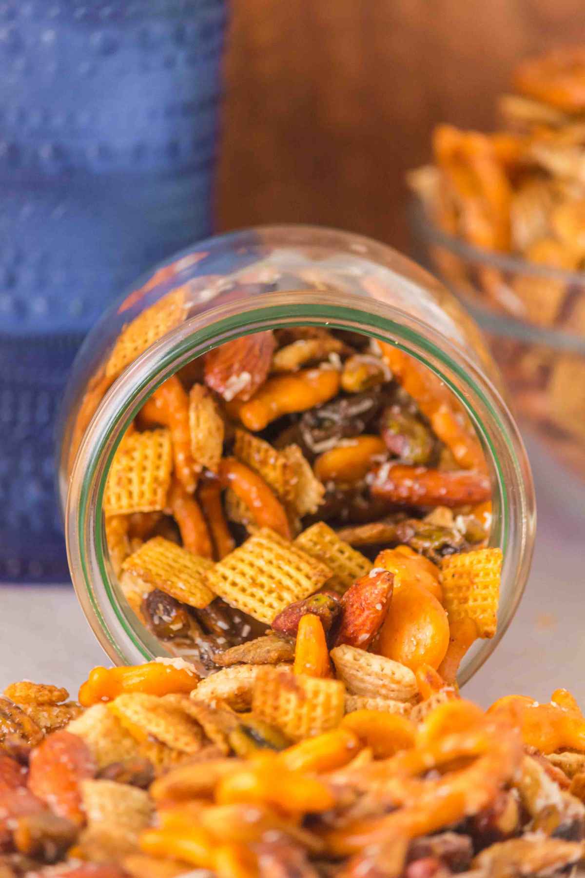 Sweet and Salty Chex Mix with pretzels and nuts spilling out of a glass storage jar.