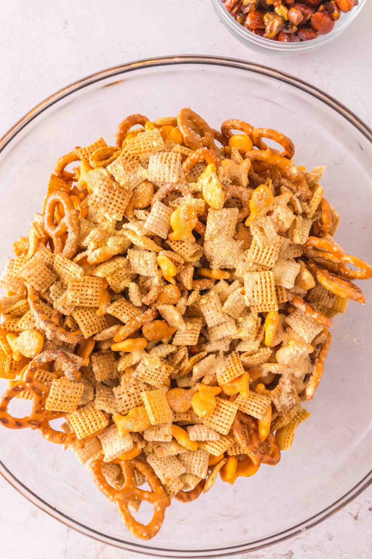 A large glass bowl filled with a variety of snack mix ingredients ready to be served.